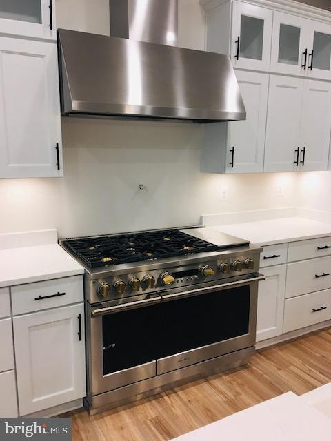 kitchen featuring light countertops, white cabinets, double oven range, and extractor fan