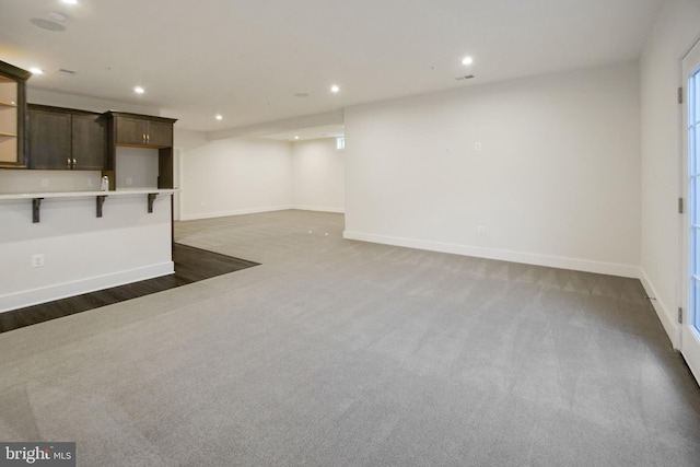 unfurnished living room featuring recessed lighting, baseboards, and dark colored carpet