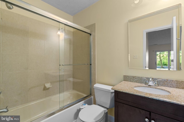 bathroom with vanity, combined bath / shower with glass door, toilet, and a textured ceiling