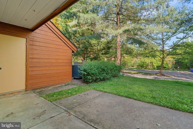 view of grassy yard featuring central AC unit and a patio area