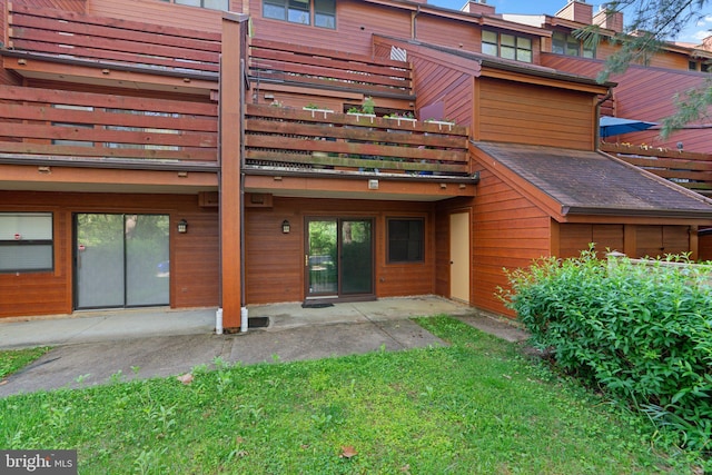rear view of property featuring a balcony, a chimney, a patio, and a yard