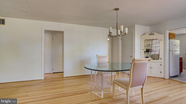 dining area with light wood-style floors, baseboards, a notable chandelier, and visible vents