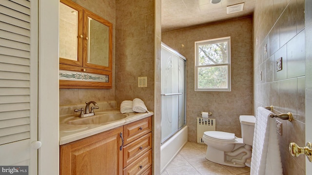 bathroom featuring vanity, toilet, tile patterned floors, radiator heating unit, and tile walls