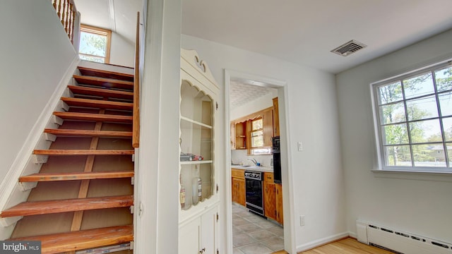 stairway with visible vents and a baseboard heating unit