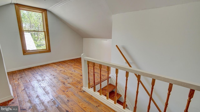stairway featuring baseboards, vaulted ceiling, and hardwood / wood-style flooring