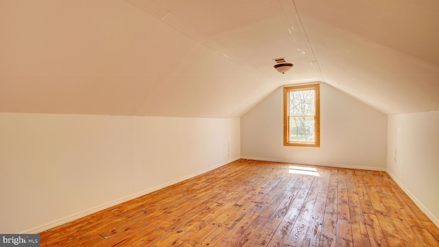additional living space featuring baseboards, vaulted ceiling, and light wood-type flooring