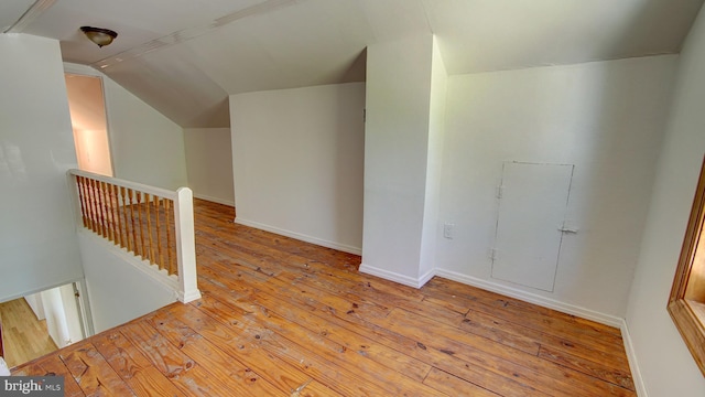 bonus room with wood-type flooring, baseboards, and vaulted ceiling