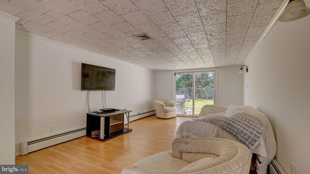 living room with visible vents, crown molding, wood finished floors, and baseboard heating