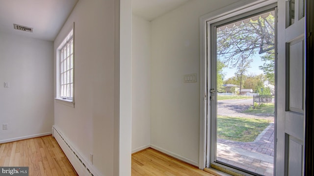doorway to outside featuring baseboards, baseboard heating, and light wood finished floors