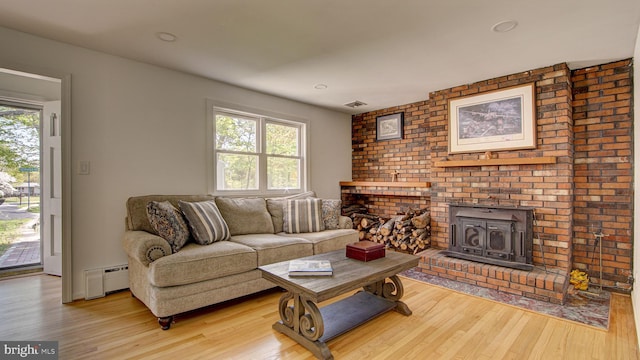 living area featuring visible vents, light wood finished floors, and a baseboard heating unit