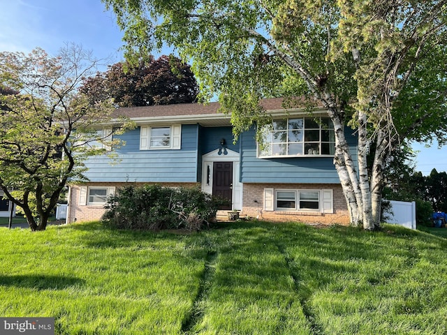 raised ranch with brick siding and a front yard