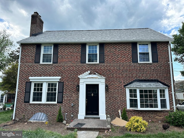view of front of property featuring a chimney and brick siding