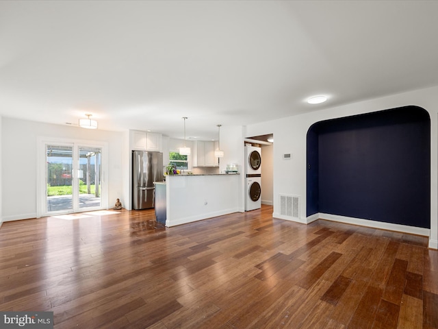 1904 N Amelia St, Sterling, VA 20164 - unfurnished living room featuring stacked washer / dryer, dark wood-style floors, and arched walkways