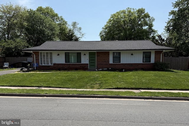ranch-style house featuring brick siding, a front lawn, and fence