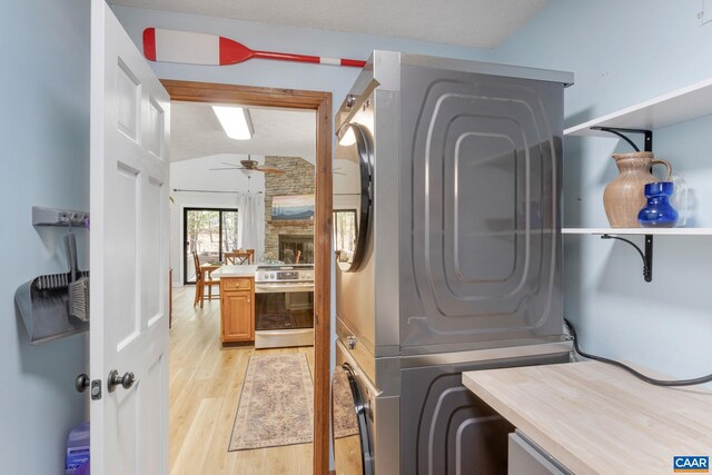 laundry area featuring light wood-type flooring, ceiling fan, laundry area, and stacked washer / drying machine
