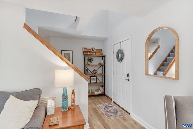 foyer entrance with stairway, baseboards, light wood-type flooring, and arched walkways