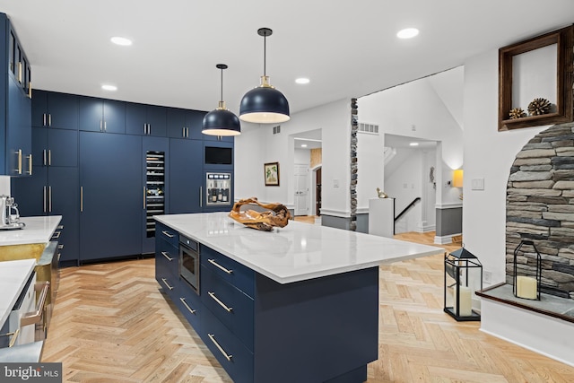 kitchen with a center island, decorative light fixtures, blue cabinets, and visible vents