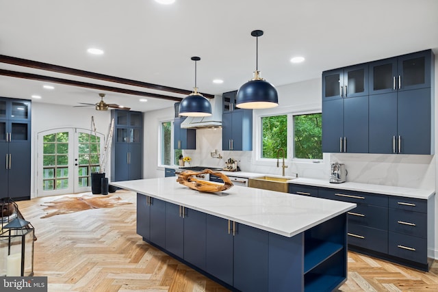 kitchen with a sink, tasteful backsplash, a wealth of natural light, and blue cabinetry