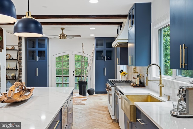 kitchen featuring high end stove, light stone countertops, blue cabinetry, and a wealth of natural light