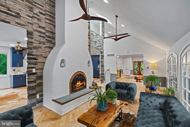 living area with ceiling fan, visible vents, high vaulted ceiling, a glass covered fireplace, and recessed lighting