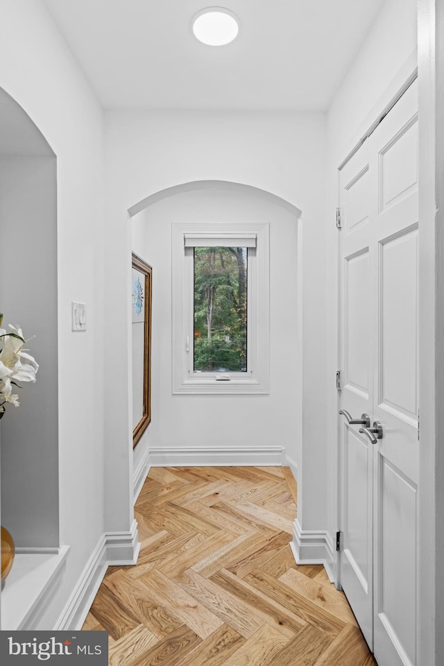 corridor with baseboards and arched walkways