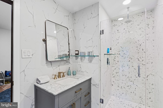 full bath with a marble finish shower and vanity