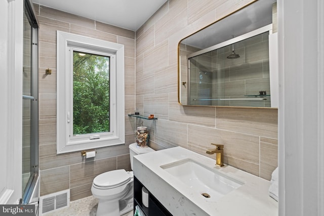 bathroom featuring visible vents, toilet, tiled shower, and tile walls