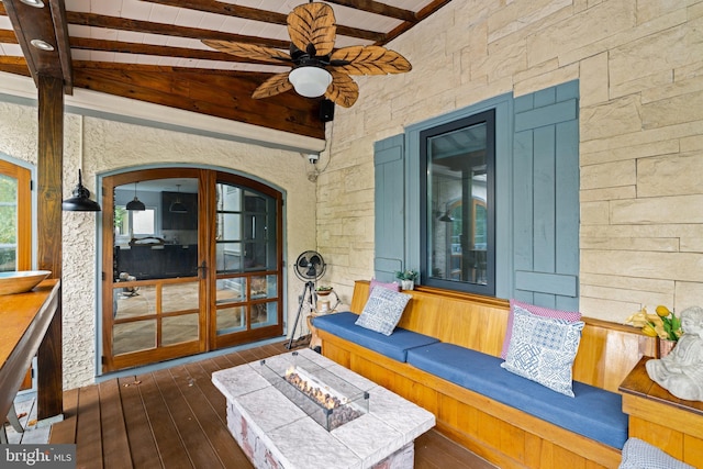 wooden terrace with french doors, ceiling fan, and a fire pit