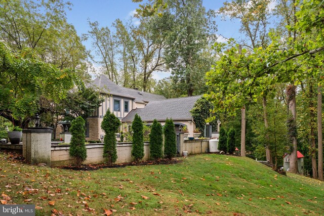 view of property exterior featuring roof with shingles, fence, and a yard