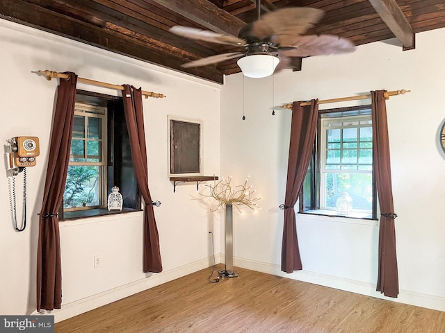 spare room with baseboards, a ceiling fan, beamed ceiling, and wood finished floors