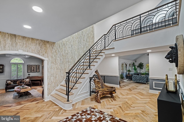 entrance foyer with a towering ceiling, wainscoting, stairs, baseboards, and recessed lighting