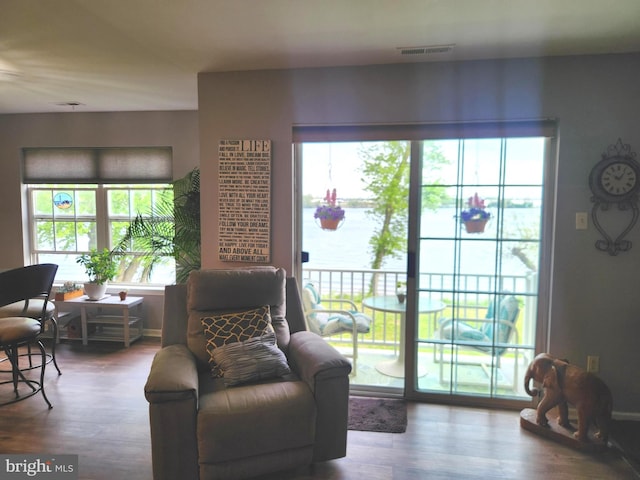 living area featuring visible vents, a water view, wood finished floors, and a wealth of natural light