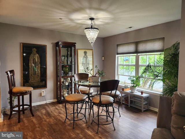dining space featuring baseboards, a chandelier, wood finished floors, and visible vents