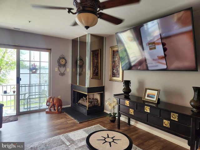 living room with dark wood-style flooring, a ceiling fan, baseboards, and visible vents