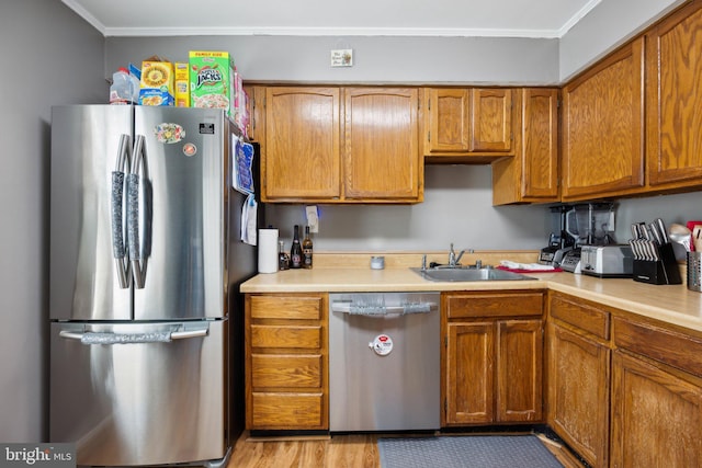 kitchen featuring light countertops, appliances with stainless steel finishes, brown cabinets, and a sink