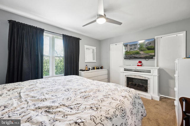 carpeted bedroom with a fireplace and ceiling fan