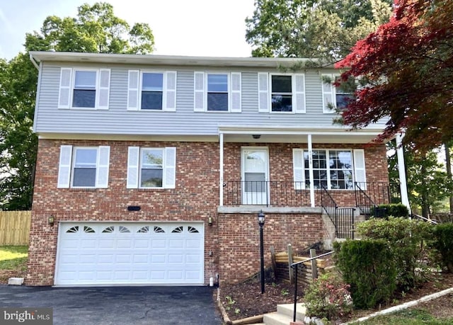 view of front of home featuring driveway, a garage, stairway, brick siding, and fence