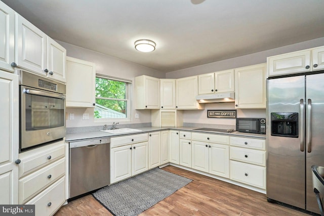 6368 Waterway Dr, Falls Church, VA 22044 - kitchen featuring black appliances, a sink, under cabinet range hood, light wood-style floors, and white cabinetry