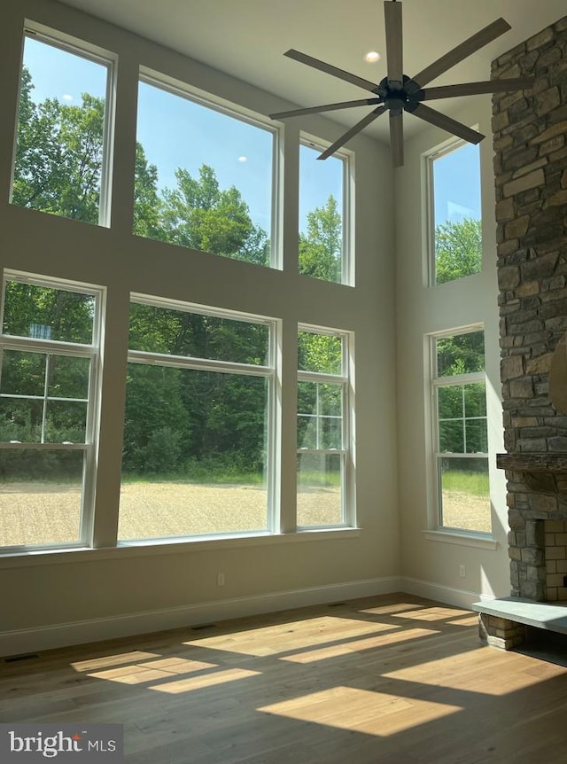 interior space featuring baseboards, plenty of natural light, a ceiling fan, and hardwood / wood-style floors