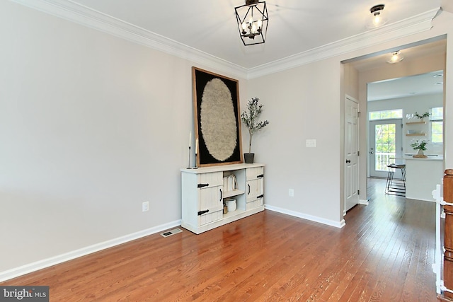 unfurnished living room featuring visible vents, ornamental molding, baseboards, hardwood / wood-style flooring, and a notable chandelier