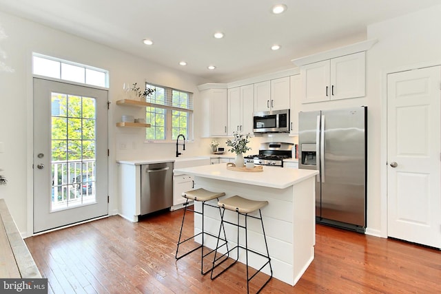 kitchen featuring white cabinetry, appliances with stainless steel finishes, wood finished floors, and a center island