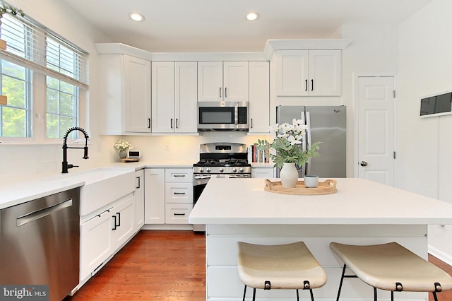 kitchen featuring a kitchen breakfast bar, stainless steel appliances, recessed lighting, and white cabinetry