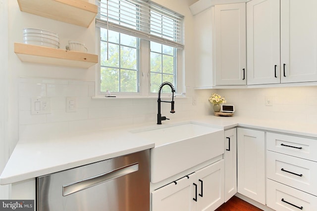 kitchen featuring stainless steel dishwasher, decorative backsplash, light countertops, white cabinets, and a sink
