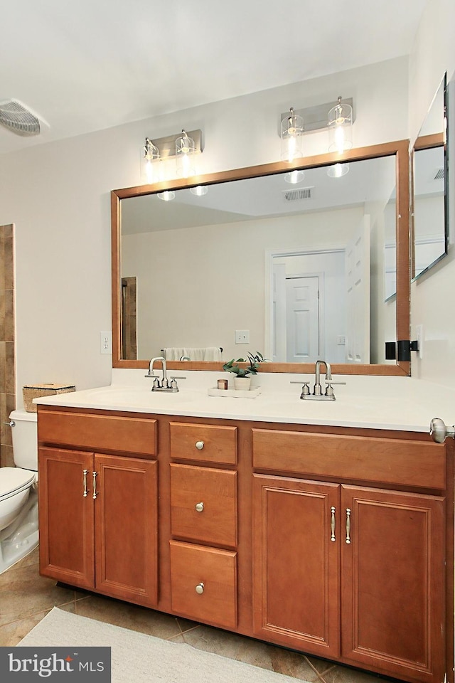 full bath with visible vents, a sink, double vanity, and toilet