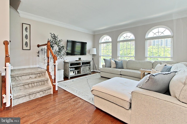living room featuring crown molding, baseboards, wood finished floors, and stairway