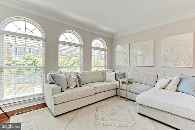 living area with crown molding, visible vents, and wood finished floors