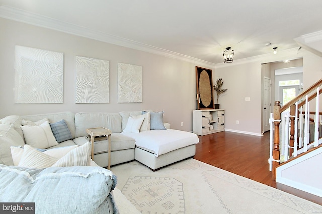 living room featuring crown molding, baseboards, stairway, and wood finished floors