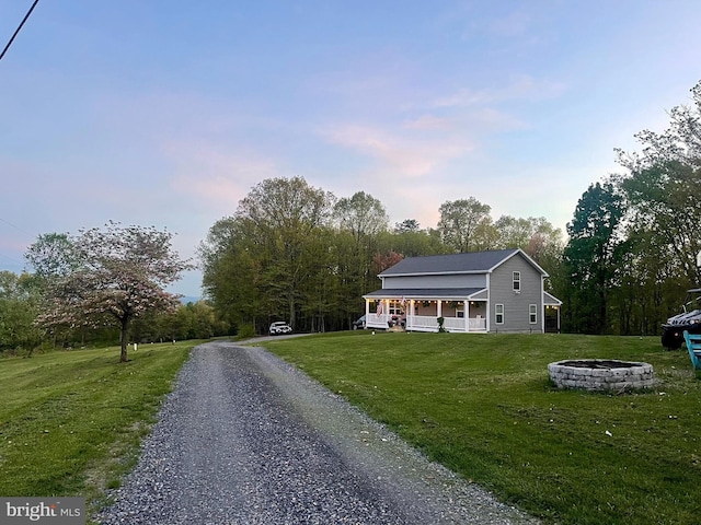 view of front of home featuring a front lawn, a fire pit, driveway, and covered porch