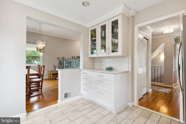 1612 Belvedere Blvd, Silver Spring, MD 20902 - kitchen with crown molding, light wood-type flooring, decorative backsplash, glass insert cabinets, and white cabinetry