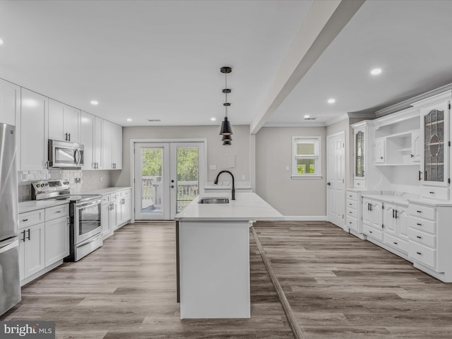 kitchen with white cabinets, appliances with stainless steel finishes, a sink, light wood finished floors, and light countertops